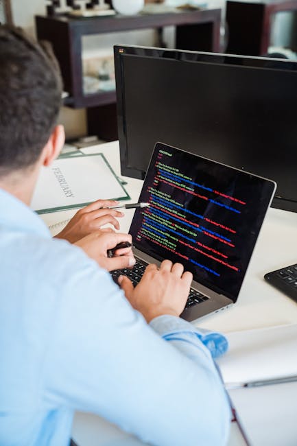 Close-up photograph of a computer screen displaying lines of HTML code in a text editor. The code features colorful syntax highlighting with tags and attributes in shades of blue, red, yellow, green,